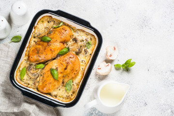 Baked chicken breast with mushrooms in cream sauce. Top view on white kitchen table.