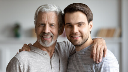 Portrait of happy young Caucasian man and senior 70s father hug enjoy family weekend together. Smiling millennial adult son feel grateful enjoy time with mature dad, show love and care in relations.