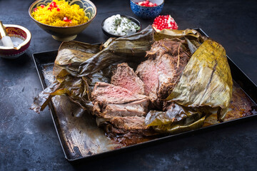 Slow cooked Omani lamb shuwa coated in rub of spices and wrapped in banana leaves served with rice...