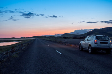 Fototapeta na wymiar Gravel road with car and dramatic sunset in southern fjords, Iceland