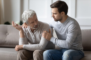 Supportive millennial Caucasian man comfort caress upset elderly 70s father feeling distressed and...