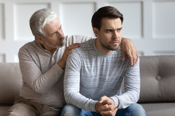 Loving elderly 70s Caucasian father hug comfort upset distressed grownup son feeling depressed or...