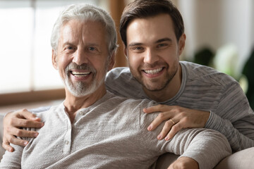 Close up portrait of smiling millennial man with mature father hug and cuddle enjoy family weekend...