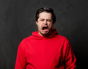 White cry guy in red sweatshirt on dark background