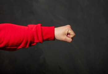 White guy in red sweatshirt show fist gesture on dark background