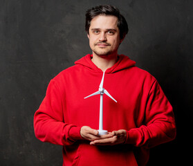 guy in red sweatshirt hold little wind generator on dark background