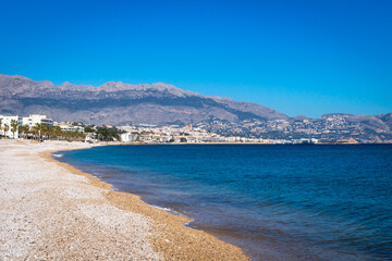 Stone beach along mediterrean sea with view to Altea seen from Albir, Spain