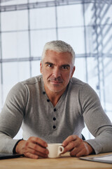 Handsome businessman having tea or coffee in office