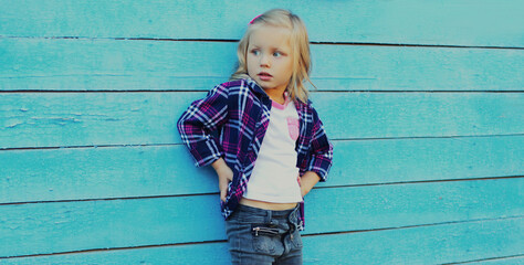 Portrait of stylish little girl child looking away posing on a blue wooden background