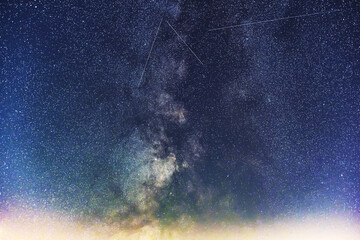 Universe with Milky Way and satellite in the night sky.