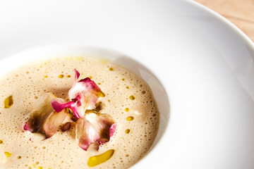Close up dish of velvety cream soup of artichokes with drops of olive oil