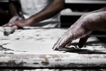 Hands of pastry chef and baker while kneading the pizza dough