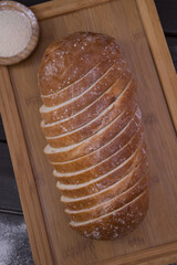Bakery - sliced golden rustic crispy loaves of bread and buns on black chalkboard background top view