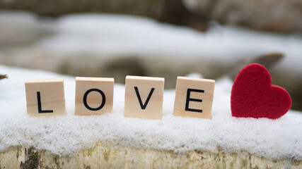 Napis LOVE z drewnianych klocków, serce w śniegu 