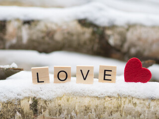 Napis LOVE z drewnianych klocków, serce w śniegu  © Klaudia Baran