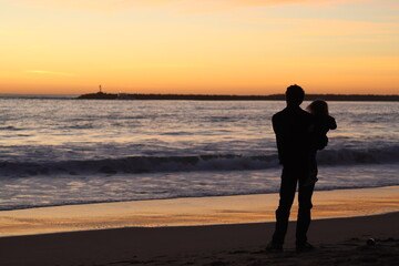 silhouette of man and child at beach during sunset