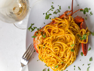Top view of spaghetti with lobster with glass of white wine