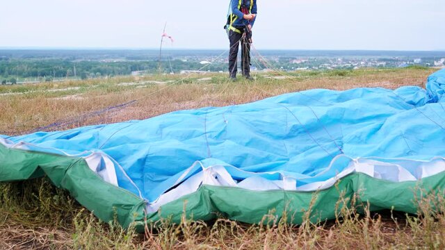 Closeup image of parachute wing lying on grass on field after parachutist landing