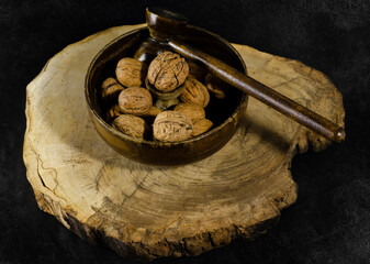 Walnut and walnut cracker in a wooden bowl. Black backround.