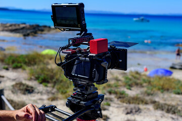 Cámara de cine digital compacta sobre tripode en playa soleada