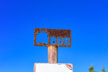 Cartel de parada bus con letras recortadas sobre cielo azul intenso