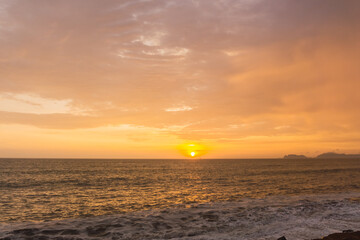 Naklejka na ściany i meble Beautiful sunset in Lima Peru, bright sky and underexposed beach, golden hour, orange sky