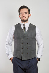 Fototapeta premium A young Latino businessman standing in a vest and tie on a white background