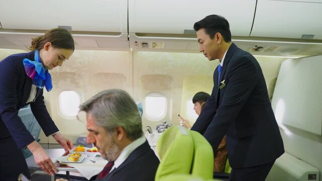 Asian flight attendant serving food and drink to passenger on airplane