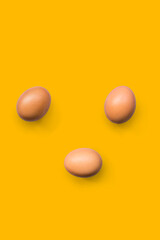 Top view close-up of fresh brown organic chicken eggs isolated on yellow background.
