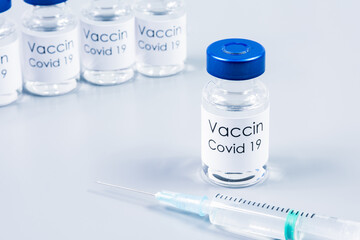 Flacons de vaccin Covid-19 et seringue sur table gris clair
