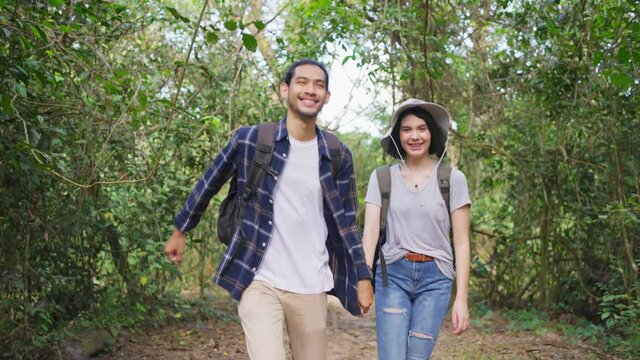 Young backpacker couple travel through a forest in the summertime.	