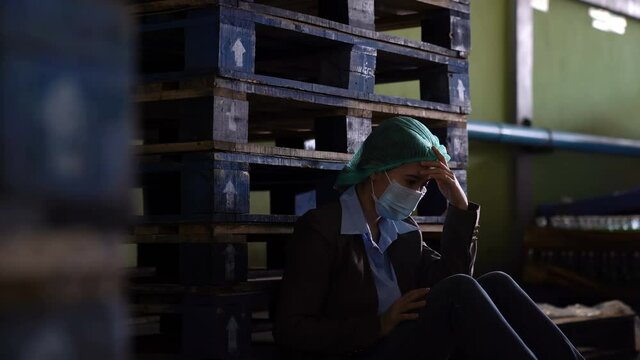 Asian Female engineer tired low energy sitting on the floor in Industry Factory feelings stressed sad and hopeless.