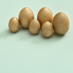 Painted Easter eggs golden colored on light green paper. Minimal easter concept. Top view spring holiday background