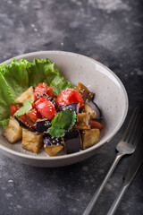 Stewed eggplant and tomato salad with slat leaf and sesame seeds served