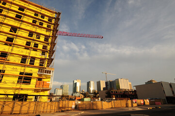 An apartment building under construction, with a tower crane visible and the downtown Phoenix, Arizona, skyline in the background © Eduardo Barraza