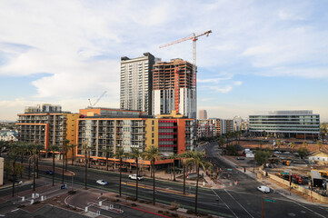 A high-rise tower under construction rises above downtown Phoenix, surrounded by modern apartments, office buildings, and active streets, illustrating ongoing urban growth and development. © Eduardo Barraza