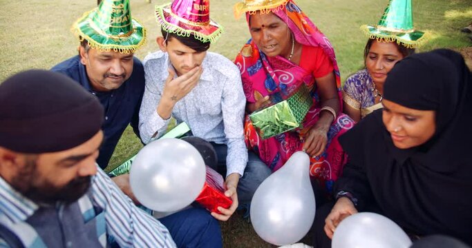 Slow-motion of mixed age group of adults, males and females, celebrating joyous enjoying with balloons, wrapped gifts and take selfie on mobile phones outdoors in summer, looking. atcamera pov