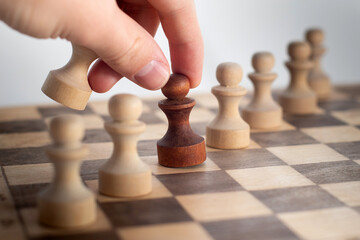 Hand taking his next step on chess game. Human hand moving dark chess pawn piece on Chess board