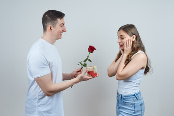 A man in love gives a surprised blonde a gift and a red rose. Happy Valentine's Day. Marriage proposal.