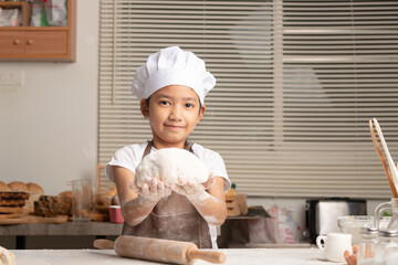 Asian little girl showing make the dough for a homemade bakery