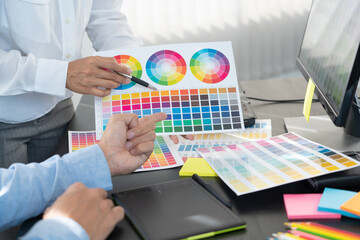 graphic designer team working on web design using color swatches editing artwork using tablet and a...