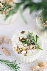 Homemade cream cheese with nuts and rosemary greens on light textile background, selective focus