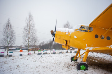 The front of the yellow small plane with two pairs of wings and a propeller in front against the...