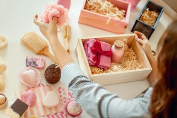 Young woman placing handmade organic bath supplies into bridesmaid gift box set.