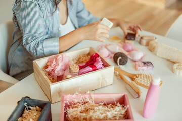 Obraz na płótnie Canvas Young woman placing handmade organic bath supplies into bridesmaid gift box set.