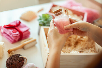Young woman placing handmade organic bath supplies into bridesmaid gift box set. - obrazy, fototapety, plakaty