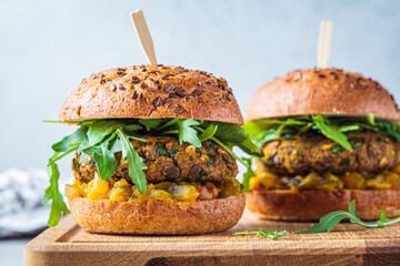 Vegan lentil burger with arugula, mustard sauce, fresh vegetables and sweet potato fries on wooden...