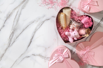 Top view of pink colored heart shaped gift boxes with homemade bath supplies, marshmallow sweets