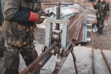 Workers bending metal at a construction site. Technology