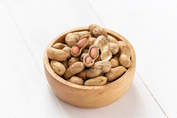 Peanuts in a wooden bowl on white background,